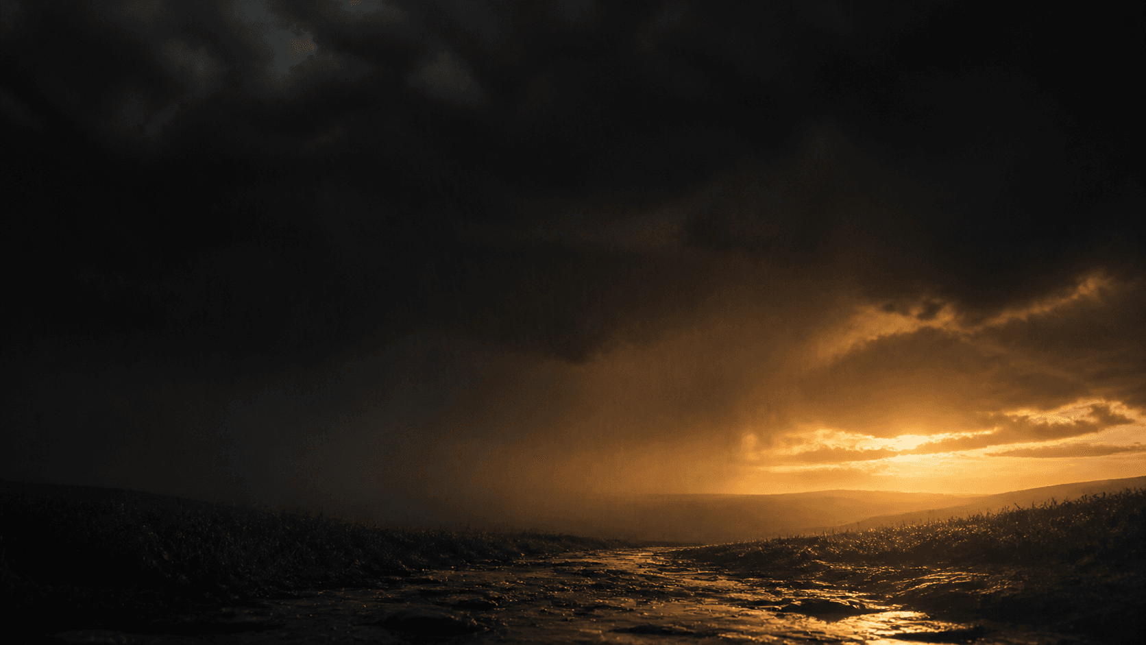 Golden light breaking through a dark rainstorm over a weathered path